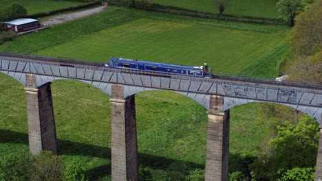 Aerial-view-following-narrow-boat-on-Trevor-basin-Pontcysyllte-aqueduct-crossing-in-Welsh-valley-countryside-slow-tracking-left