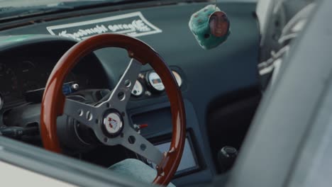 Steering-wheel,-fuzzy-dice-in-interior-of-drift-car,-close-up-dolly-out