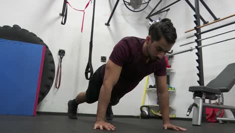 Dark-haired-man-with-beard-does-push-ups-and-holds-himself-just-above-the-floor