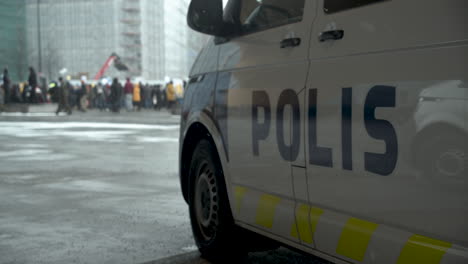 Weitwinkelaufnahme-Eines-Polizeiwagens-Mit-Den-Demonstranten,-Die-Sich-In-Helsinki-Wegen-Der-Covid-19-Beschränkungen-Im-Hintergrund-Versammeln