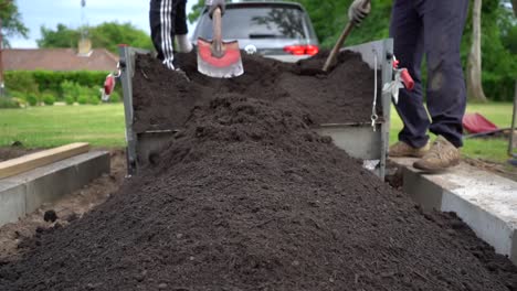 Topsoil-Being-Hand-Shovelled-From-Car-Trailer-Into-Garden-Flower-Bed