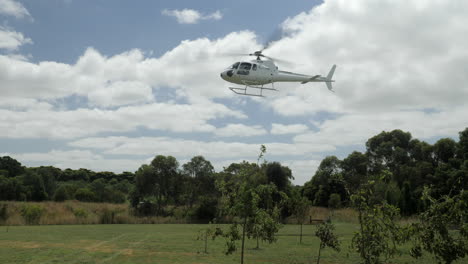 SLOW-MOTION-Charted-Helicopter-Hovers-To-Land-Over-Grassy-Field