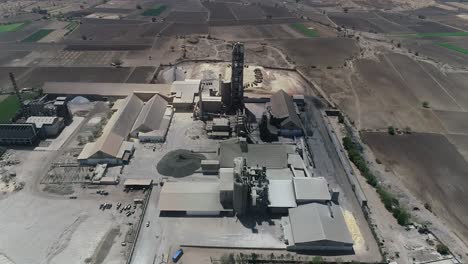 Aerial-view-of-a-small-plant-for-the-production-and-cleaning-rubble-and-cement-near-the-heaps-of-building-materials-from-the-pipe-of-which-gray-smoke-goes,-the-tractor-transports-the-finished-product