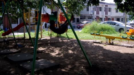 Niño-Disfrutando-Del-Columpio-En-Un-Parque-Infantil-Dentro-De-Una-Subdivisión-Residencial-En-La-Ciudad-De-Mandaue,-Filipinas