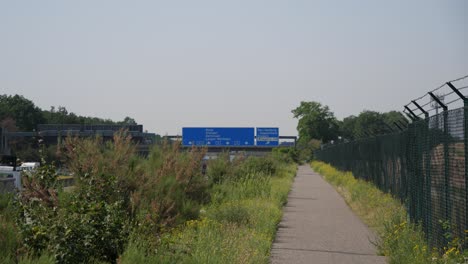 Establishment-shot-of-traffic-sing-at-the-A5-Highway-below-the-signage-shows-the-direction-to-Cargocity-Süd-Airport-in-Frankfurt,-Germany