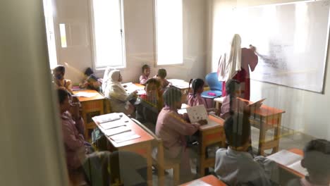Female-Muslim-Teacher-Wiping-Whiteboard-In-Classroom-With-Children-In-Pakistan