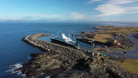 Car-and-passenger-ferry-Raunefjord-behind-breakwater-at-sunny-day-in-Mortavika-Norway---Approaching-aerial-in-sunny-weather-with-ocean-in-background