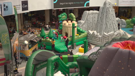 inflatable-crocodile-and-palm-trees-for-kids,-jumping-on-inflatable-slide-in-mall
