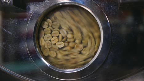 Close-up-of-freshly-dried-green-coffee-beans-tumbling-around-in-roasting-machine
