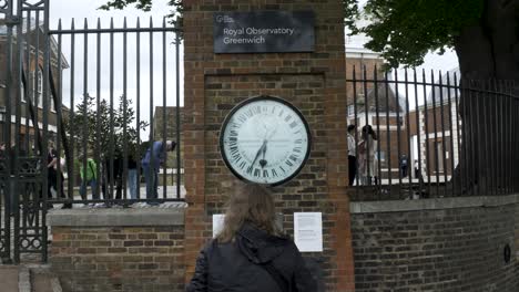 Visitor-Standing-In-Front-Of-Wall-Clock-Beside-Gates-At-Royal-Observatory-Greenwich-On-7-May-2022