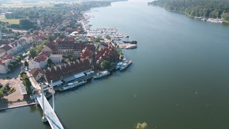 Mikolajki,-Poland---Drone-flight-aerial-bird-flyover-the-city-center-of-Mikolajki-following-the-coast-of-the-blue-lake-with-restaurants-tiny-boats-and-yachts
