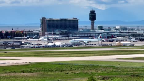 Vancouver-International-Airport--View-Of-The-YVR-Plane-And-Passenger-Terminal-With-Sight-Of-A-Landing-Aircraft-In-Richmond,-British-Columbia,-Canada-During-The-Day
