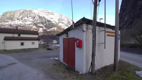 Smallest-firestation-in-Europe-located-in-Undredal-Norway---Slowly-rotating-around-firestation-at-ground-level-with-snowy-mountain-background