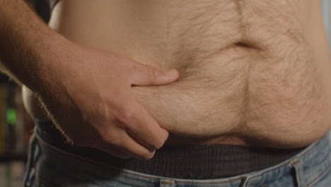Close-up-of-Shirtless-man-grabbing-belly-fat-and-grabbing-love-handle---front-view