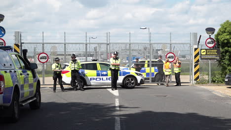 Police-officers-stand-guard-at-a-security-gate-entrance-to-Brook-House-Immigration-Removal-Centre-as-a-plane-lands-at-Gatwick-Airport