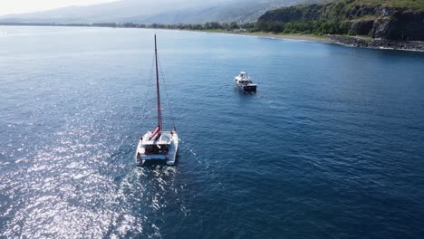 Drohnenaufnahmen-Eines-Katamarans-Mit-Menschen-Und-Einem-Anderen-Boot-In-Der-Nähe-Einer-Klippe-Auf-Der-Insel-La-Réunion