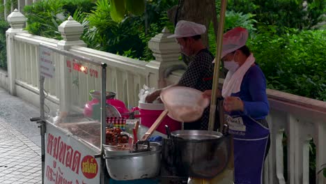 Zwei-Frauen-Verkaufen-Lokales-Streetfood,-Kleiner-Straßenstand-In-Der-Nähe-Von-Silom,-Bangkok