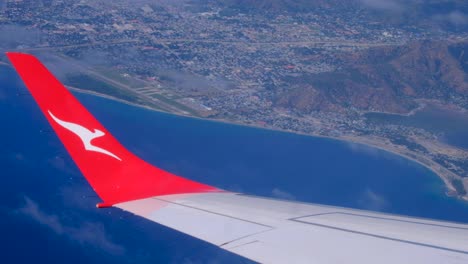 Avión-De-Qantas-Con-El-Logotipo-De-Canguro-En-El-Ala,-Vuelo-Que-Llega-A-Dili-Timor-Leste-Desde-Darwin-Australia-Con-Vistas-A-La-Costa-Del-País-Y-Al-Océano-Desde-La-Ventana-Del-Avión