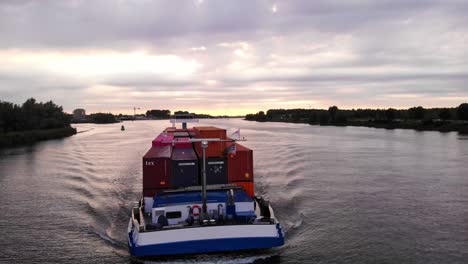 Aerial-Parallax-Left-Around-Forward-Bow-Of-Levante-Cargo-Container-Transport-Ship-Along-Oude-Maas-Against-Sunset-Skies