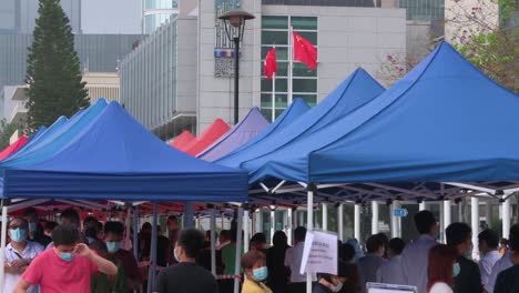 China's-and-Hong-Kong-flag-wave-in-the-wind-as-people-queue-in-line-to-receive-PCR-tests-for-coronavirus-from-a-Community-Testing-Centre-truck-to-tackle-the-spread-of-the-virus