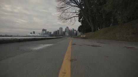 Weitwinkelaufnahme-Des-Seawall-Trail-Mit-Gelber-Linie-Und-Der-Skyline-Von-Vancouver-Im-Hintergrund,-Morgen,-Zeitlupe
