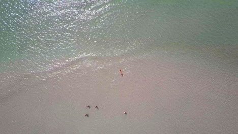 Raising-drone-view-of-a-group-of-people-relaxing-by-a-heaven-looking-calm-beach