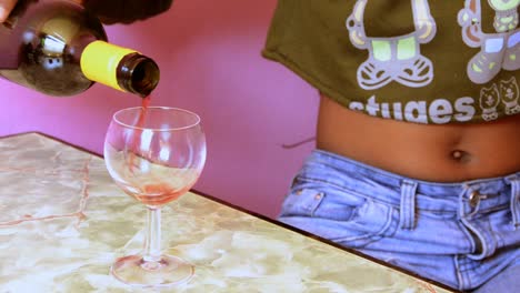 African-woman-pouring-wine-into-a-glass-and-spilling-on-the-table-in-a-bar-or-hotel-room