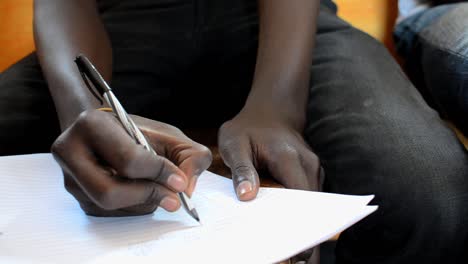 Primer-Plano-De-La-Mano-De-Un-Joven-Escribiendo-En-Un-Seminario-En-Kibera,-Nairobi,-Kenia-2