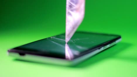 The-knife-fits-into-the-touch-screen-of-the-smartphone-on-green-background