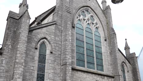 Eine-Aufnahme-Der-Rückseite-Der-St.-Augustine-Kirche-In-Der-Stadt-Galway,-Eingerahmt-Neben-Einem-Lichtmast,-Aufgenommen-In-Zeitlupe-4K