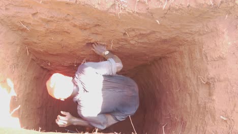 Birds-eye-view-looking-down-into-a-dug-out-pit-latrine-in-Africa-with-a-young-worker-climbing-out-of-the-deep-hole