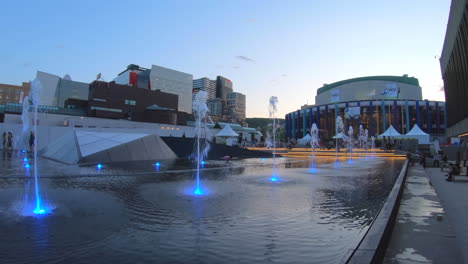 Editorial,-established-shot,-view-of-public-outdoors-water-fountain-at-place-des-festivals-Montreal,-sunset-moment-and-beautiful-blue-sky
