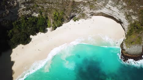 Bird's-Eye-Drone-shot-above-waves-crashing-onto-KelingKing-beach-on-the-island-of-Nusa-Penida,-Indonesia