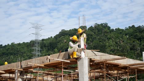 Bauarbeiter,-Die-Auf-Der-Baustelle-Holzschalungen-Und-Regenwasserrohre-Installieren