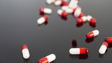 Rote-Medikamentenkapseln-Und-Verschreibungspflichtige-Medikamentenpillen-Fallen-In-Zeitlupe-Auf-Einem-Schwarzen,-Isolierten-Hintergrund