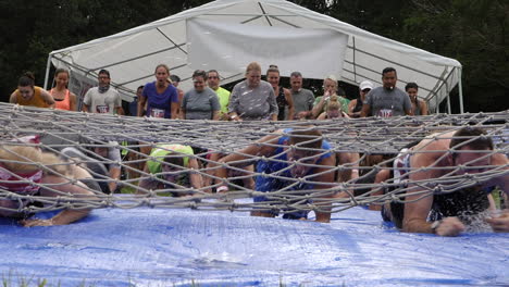 Mud-Run-Participants-crawling-under-a-cargo-net-slip-and-slide-obstacle