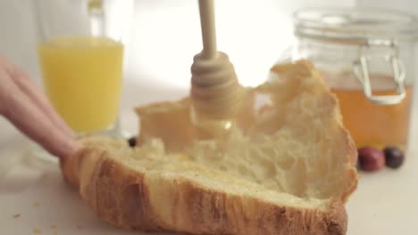 Drizzling-honey-on-fresh-baked-croissant-medium-shot