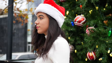 Frau-Mit-Weihnachtsmütze-Feiert-Die-Fröhliche-Weihnachtszeit-Mit-Einem-Weihnachtsbaum,-Ornamenten-Und-Lichtern