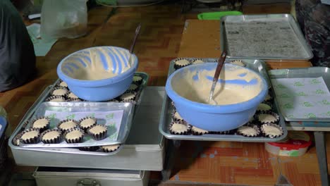 Unbaked-cupcakes-in-baking-cups-and-bowls-of-cupcake-batter-in-small-Thai-bakery