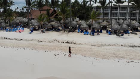 Woman-walking-on-beautiful-tropical-beach,-aerial-panning-shot