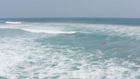 Surfers-With-Boards-in-Pacific-Ocean-on-Summer-Day,-Aerial-View