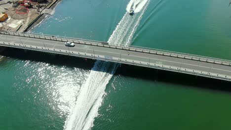 Boat-and-Jet-Ski,-racing-out-under-bridge-Gold-Coast-Australia