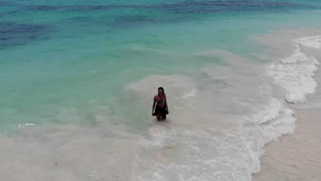 Woman-walking-into-sea-on-beautiful-tropical-beach,-aerial-circle-pan