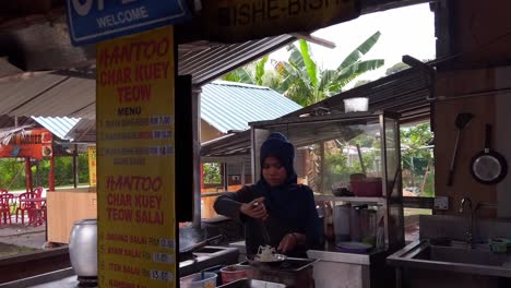 Mujer-Sirviendo-Comida-Frita-En-Un-Restaurante-Local-De-Comida-Callejera-De-Malasia