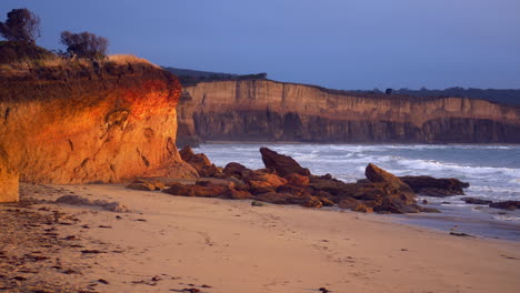 Eroded-Golden-Sandstone-Seaside-Cliffs-During-Sunset,-PAN-RIGHT