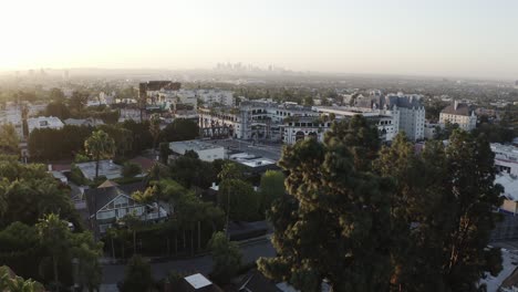 Aerial-drone-shot-in-West-Hollywood-looking-out-toward-the-tall-skyscraper-of-downtown-LA-at-sunset