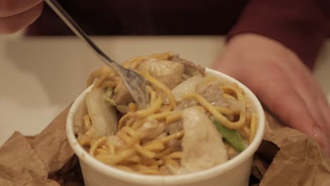 Thai-green-curry-noodles-with-meat-mixed-being-forked-for-meal,-closeup
