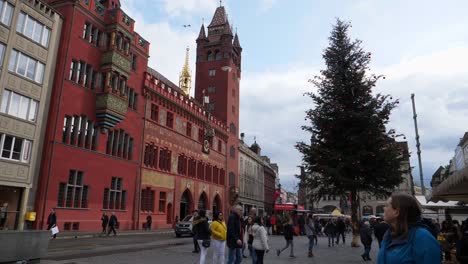 Full-shot,-tourist-in-front-of-town-hall-in-Basel,-Switzerland,-christmas-tree-with-red-ornaments-in-the-background