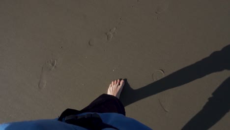 Personal-POV-of-Man's-Feet-Walking-on-Sandy-Beach-With-a-Shadow-of-Evening-Sun