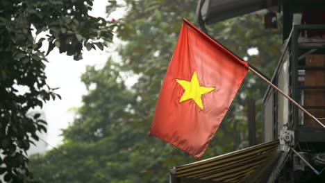 Vietnamese-Flag-In-A-Wooden-Stick-Hanging-Outside-In-Hanoi,-Vietnam---Closeup-Shot